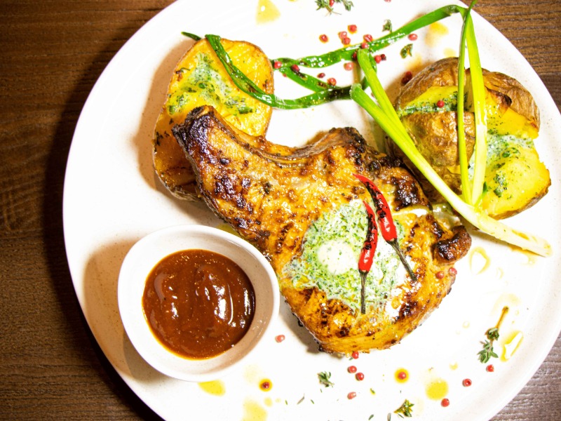 Корейка на кістці з печеною картоплею та зеленим маслом